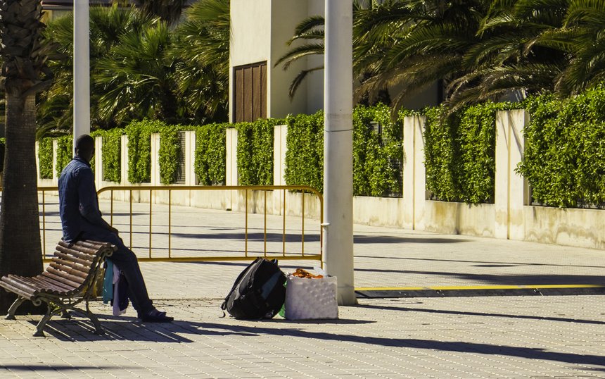 An African man with full bags in a European city stopped before 