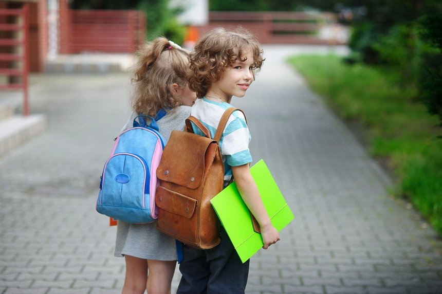 Two little pupil of elementary school, boy and girl, stand having joined hands