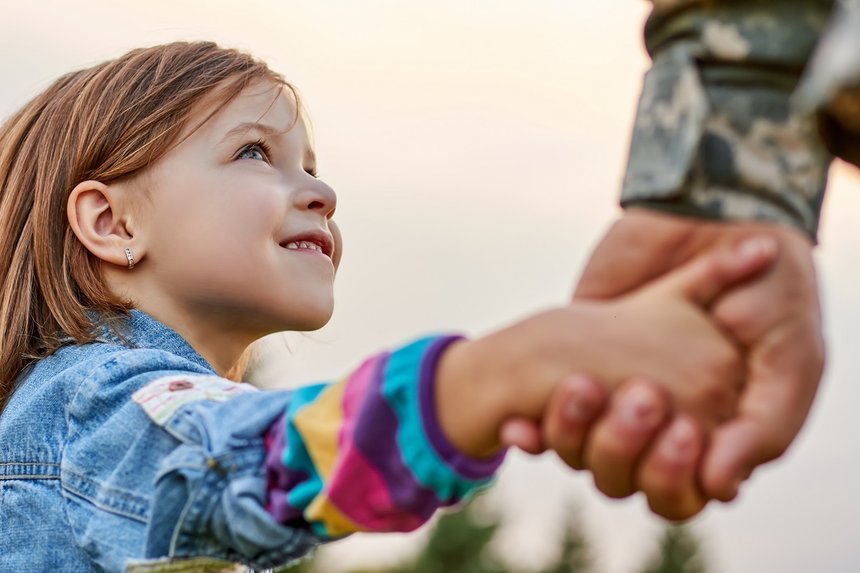 Close up portrait little girl looks at his military father. Lovely gaze of a daughter, holding hands.