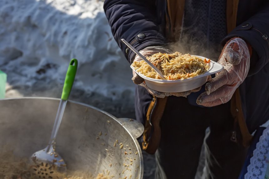 Plate with pilaf in male hands. Street food. Help for homeless.
