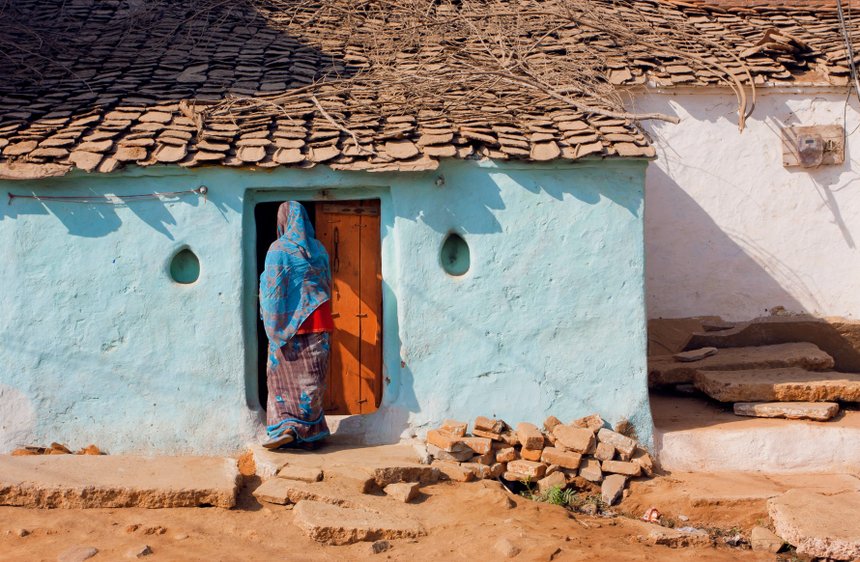 House of poor family and indian woman standing at the door
