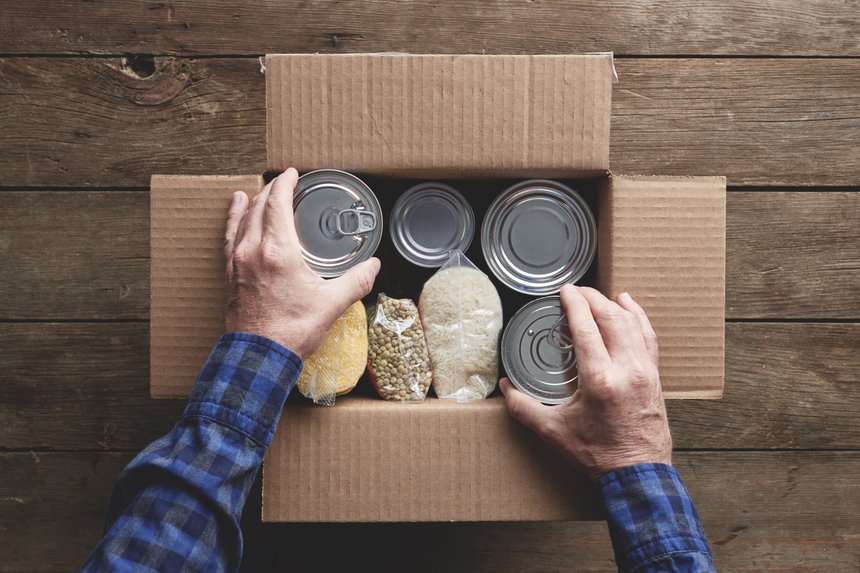 a person packing a donation box with food items