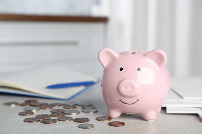 Piggy bank and coins on light table indoors, space for text. Money savings