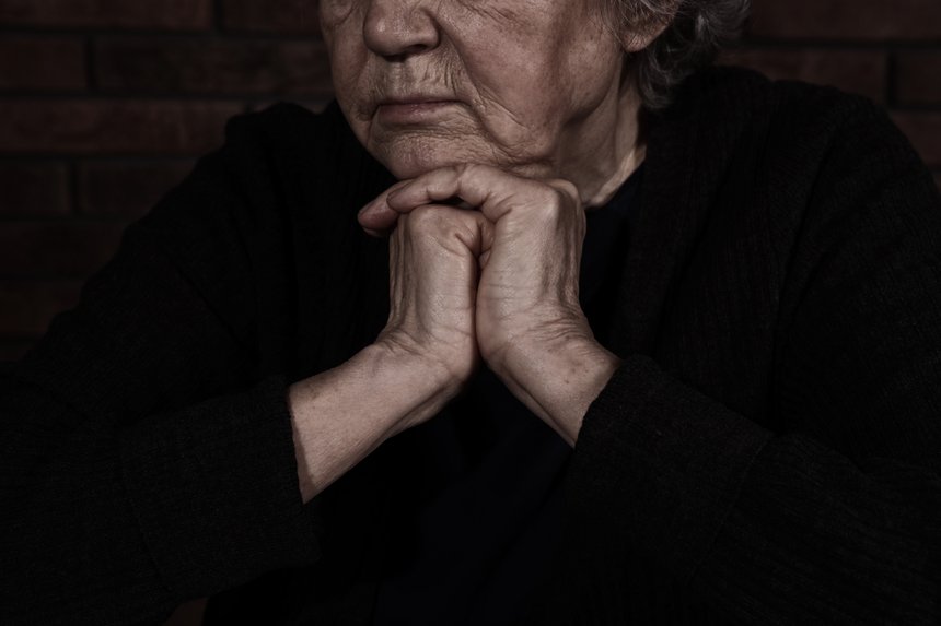 Poor mature woman on dark background, closeup