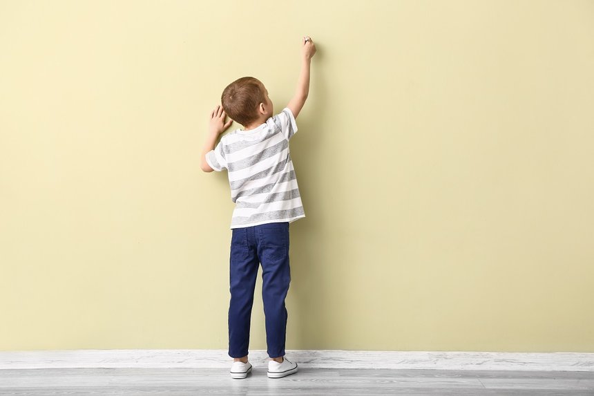Little boy drawing on color wall