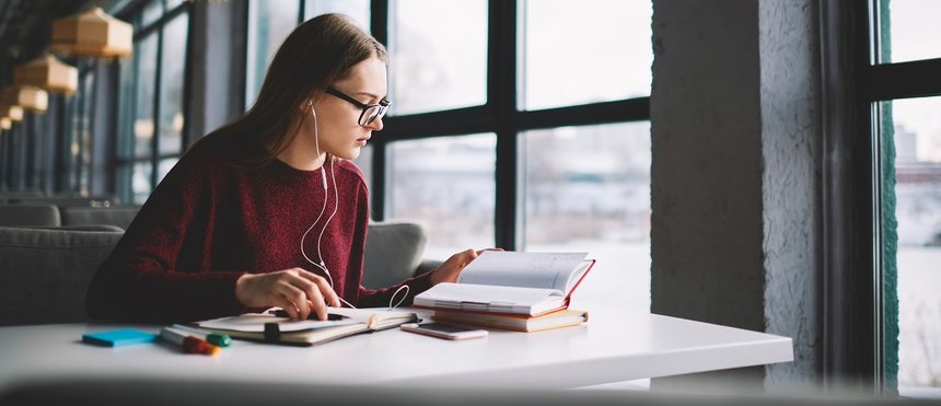 Attractive hipster girl learning at university library while enj