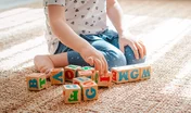 child plays with wooden blocks with letters on the floor in the