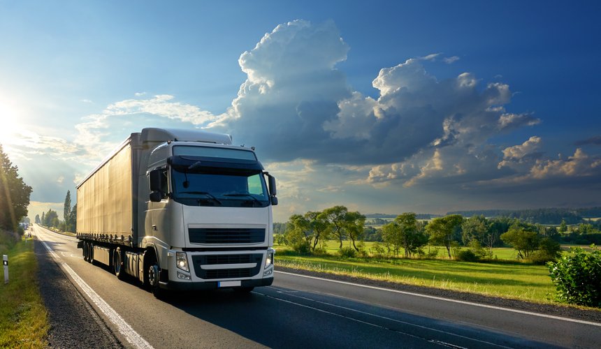 White truck arriving on the asphalt road in rural landscape in t
