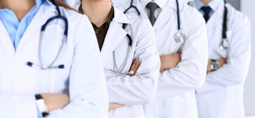 Group of modern doctors standing as a team with arms crossed in 