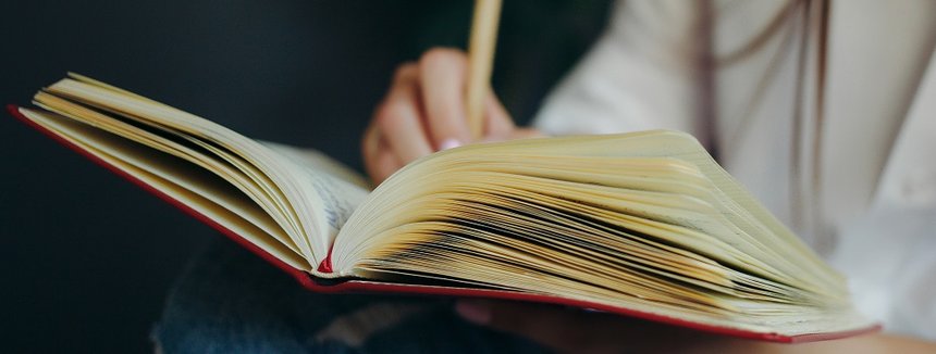 Closeup of a female hand writing on an blank notebook with a pen