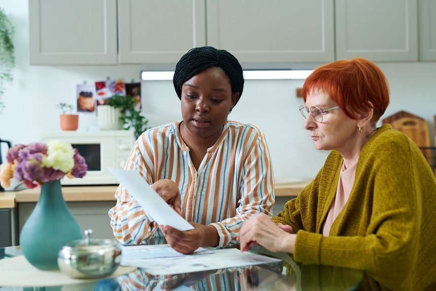African young volunteer sitting at kitchen table together with s