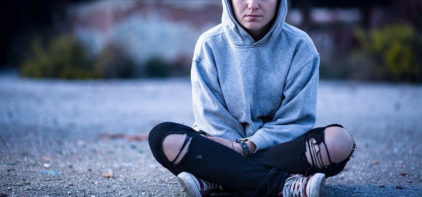 Woman with Sweatshirt and Torn Trousers Sitting on the Street