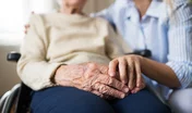 A senior woman in wheelchair with a health visitor at home at Christmas time.