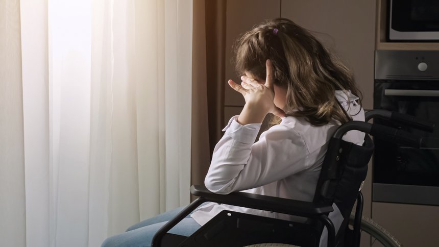 Pensive disabled woman with infantile cerebral paralysis sits in wheelchair near window behind curtain at home experiencing ableism, sunlight.