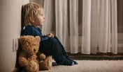 Sad little toddler child, blond boy, sitting in corner with teddy bear, punished