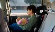 Boy with disability holding teddy bear while traveling by car
