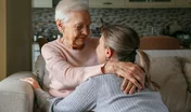 Grandmother and granddaughter hugging in the living room. Two adult women of different age. Family values concept. Close up, copy space, background.
