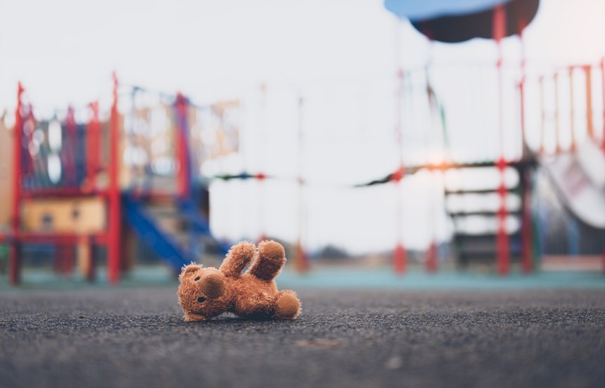 Lost teddy bear toy lying don on playground floor in gloomy day,Lonely and sad brown bear doll lied down alone in the park,lost toy or Loneliness concept,International missing Children day