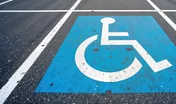 Blue handicap parking sign on asphalt road. Accessibility symbol for people with disabilities. Designated space for vehicles with disabled drivers. Street parking layout, design for better mobility.