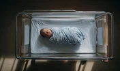 Swaddled Newborn Baby Sleeping in a Hospital Bassinet