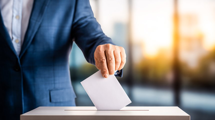 Homme en train de déposer un bulletin de vote dans une urne