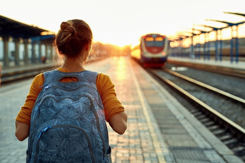 portrait of a young woman traveler with small backpack on the railway stantion