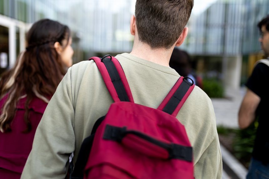 Student walking away with backpack on campus